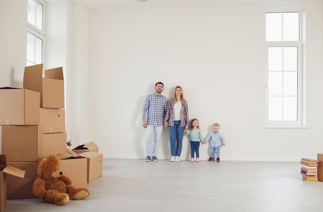 Happy Family with Children Moving with Boxes in a New Apartment House.